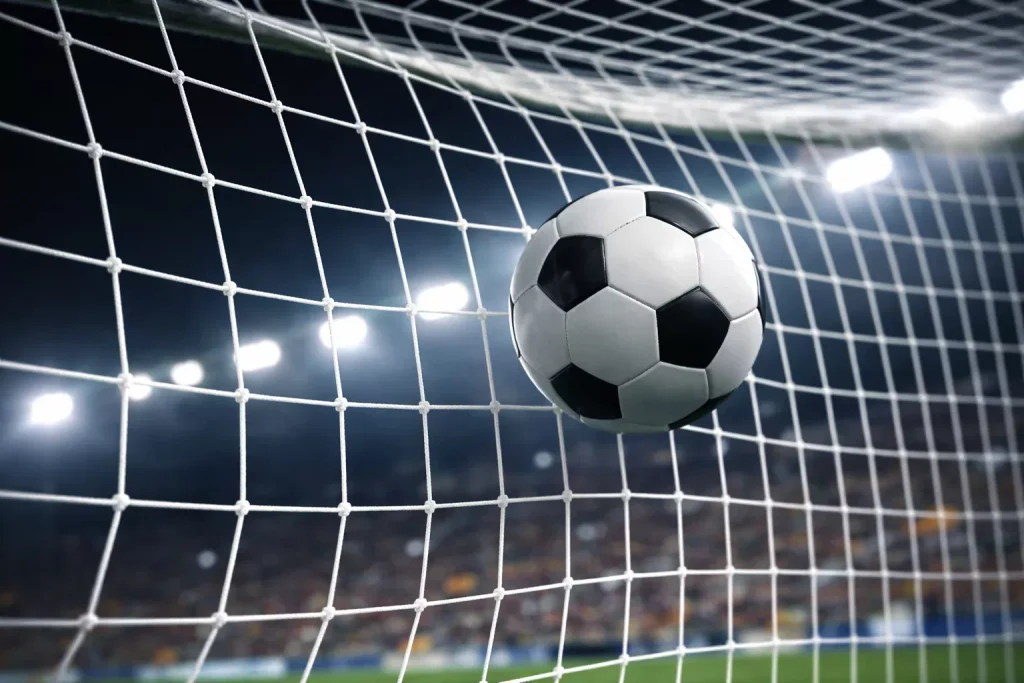 Balón de fútbol entrando en la red de una portería con iluminación dramática nocturna